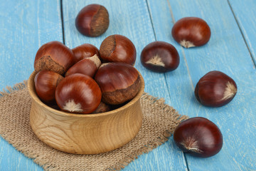 chestnut in wooden bowl on blue wooden background