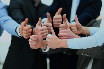 Close-up of business team holding their thumbs up.