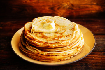 Russian Maslenitsa, Shrovetide, pancake week, carnival, shrove, pancake day. a stack of pancakes with butter upstairs on plate, on wooden background, close-up