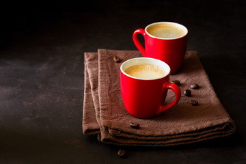Two red cups of espresso on dark wooden background decorated coffee beans