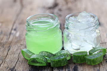 Fresh aloe vera and jelly in Glass bottle placed on a wooden floor.