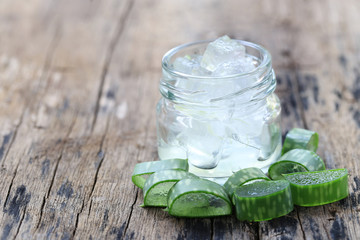 Fresh aloe vera and jelly in Glass bottle placed on a wooden floor.