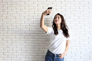 Stylish woman making selfie with shopping bag on the yellow wall background. Winter holiday sale