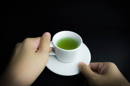 hand hold a cup of green tea drink in black background
