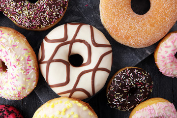 assorted donuts with chocolate frosted, pink glazed and sprinkles donuts.