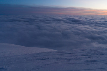 Beautiful sunset above clouds in snow covered Low Tatras mountains during susnet in winter