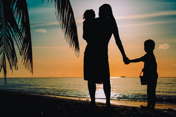 mother and two kids walking on beach at sunset