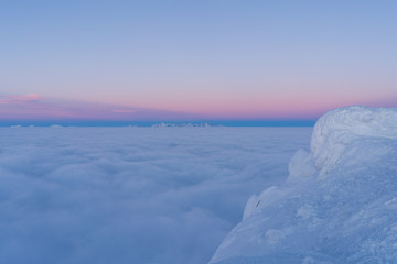 Beautiful sunset above clouds in snow covered Low Tatras mountains during susnet in winter