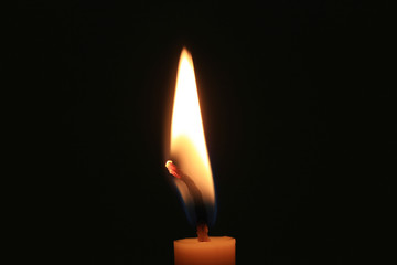 Candle flame burning on black background.