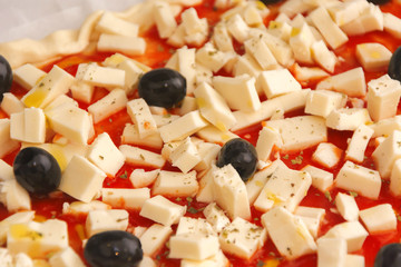 Raw pizza decorated mozzarella, black olives and tomato sauce