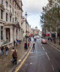 London city street scene through double decker bus window with rain drops