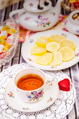 Porcelain cup of tea with lemon and sweets