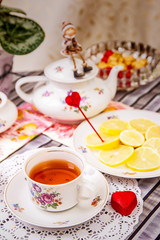 Porcelain cup of tea with lemon and sweets