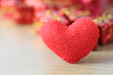 red heart placed on a wooden floor on red gift box of blur background.