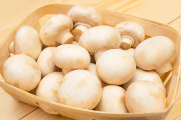Fototapeta premium fresh mushrooms champignons in a basket on a wooden background