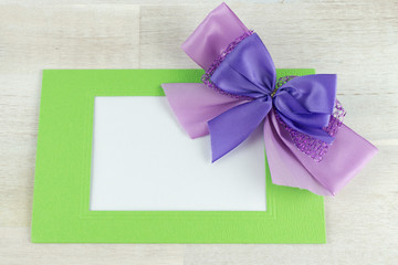 Violet ribbon with green frame with blank white copy space, wooden background