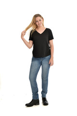 full length portrait of blonde girl wearing black shirt and jeans, standing pose isolated on a white background.