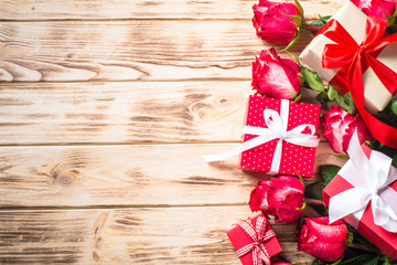 Red rose flower and present box on wooden table. 
