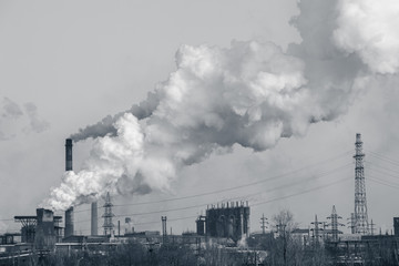 smoke stacks in a working factory emitting steam, smog and air pollution.