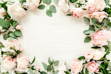 Floral pattern, frame made of pink peonies  branches of eucalyptus and leaves on wooden white...