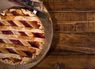 Whole cherry pie on a wooden surface with copy space