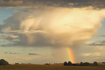 Naklejka na ściany i meble huge storm cloud is connected to earth through a beatiful rainbow