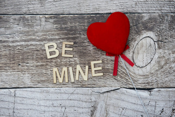 Red heart with the words be mine on a wooden background with copy space 