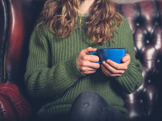 Young woman sitting on sofa with cup