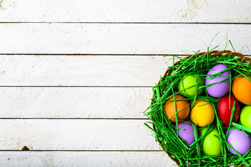 Spring easter eggs, background with colored eggs in the basket on wooden table