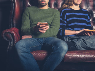 Young couple reading and using phone