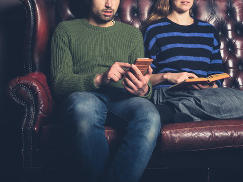 Young couple reading and using phone