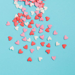 Candies hearts of pastel colors on blue paper. Flat lay.