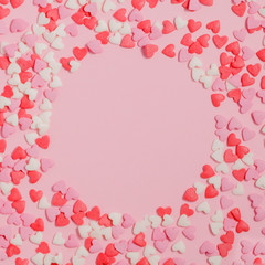 Candies hearts of pastel colors on pink paper. Flat lay. Copy space.