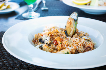 Tasty risotto with Shrimp, fresh herbs vegetables on a white plate