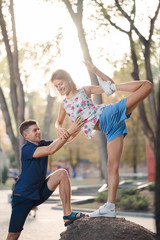 Fototapeta premium couple in love in the park, the guy helps the girl on the stone do yoga pose, laugh