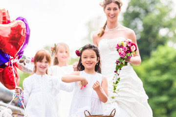 Wedding bride with flower children or bridesmaid in white dress and flower baskets