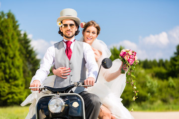 Wedding groom and bride driving motor scooter having fun 