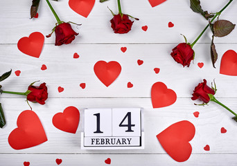 Valentines Day background with red roses, paper hearts and february 14 wooden block calendar, copy space. Greeting card mockup. Love concept. Top view, flat lay