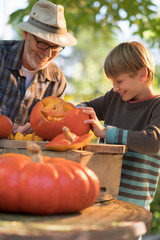 a man teaching his son how to carve a pumpkin for halloween.