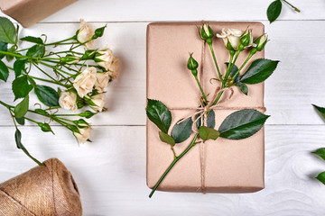 Gift boxes with branches of fresh roses on wooden table, copy space. Holiday background, sale, shopping. Gift wrapping. Greeting card for Valentines Day, Womans Day, Mothers Day, flat lay