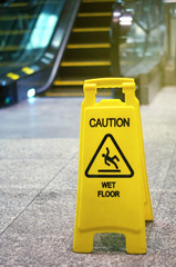 Indoor escalator with slippery when wet sign on floor