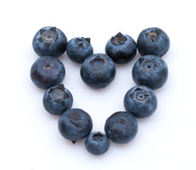 Blueberries shaped like a heart on white background