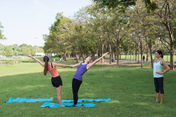 Family practicing yoga in the park outdoor. Concept of healthy lifestyle and relaxation..