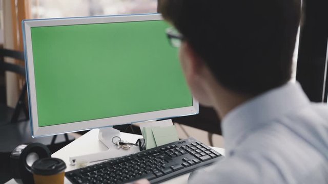Young man works with pc with green screen and keyboard . 4K