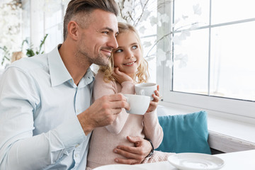young father and daughter drinking tea in cafe together
