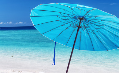 Blue umbrella with sun beds on a beautiful tropical sandy beach. Holiday concept
