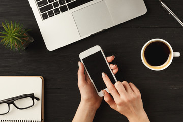Woman's hands using smartphone, top view