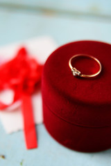 Background, texture on St. Valentine's day February 14: red heart, flowers and a red velvet box with an engagement ring on a blue wooden background, concept of love, wedding, engagement, of marriage