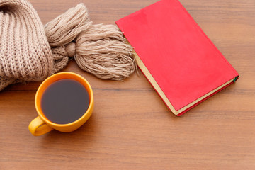 Fototapeta na wymiar Cup of coffee, knitted scarf and book on wooden background