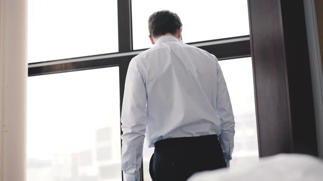 Handsome businessman waiting at windows in office. 4K